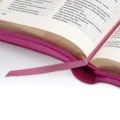 Detal, który robi różnicę: satynowa wstążka-zakładka w Biblii Malinowej na tle otwartej strony. Funkcjonalny dodatek ułatwiający powrót do ulubionych fragmentów Pisma Świętego.