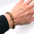 Bransoletka religijna męską z krzyżykiem z hematytu i koralikami z drewna w ciemnym odcieniu - na nadgarstku męskim