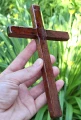 Krzyż drewniany na ścianę, handmade - drzewo egzotyczne - 20,5 cm - na tle zieleni w naturalnym świetle
